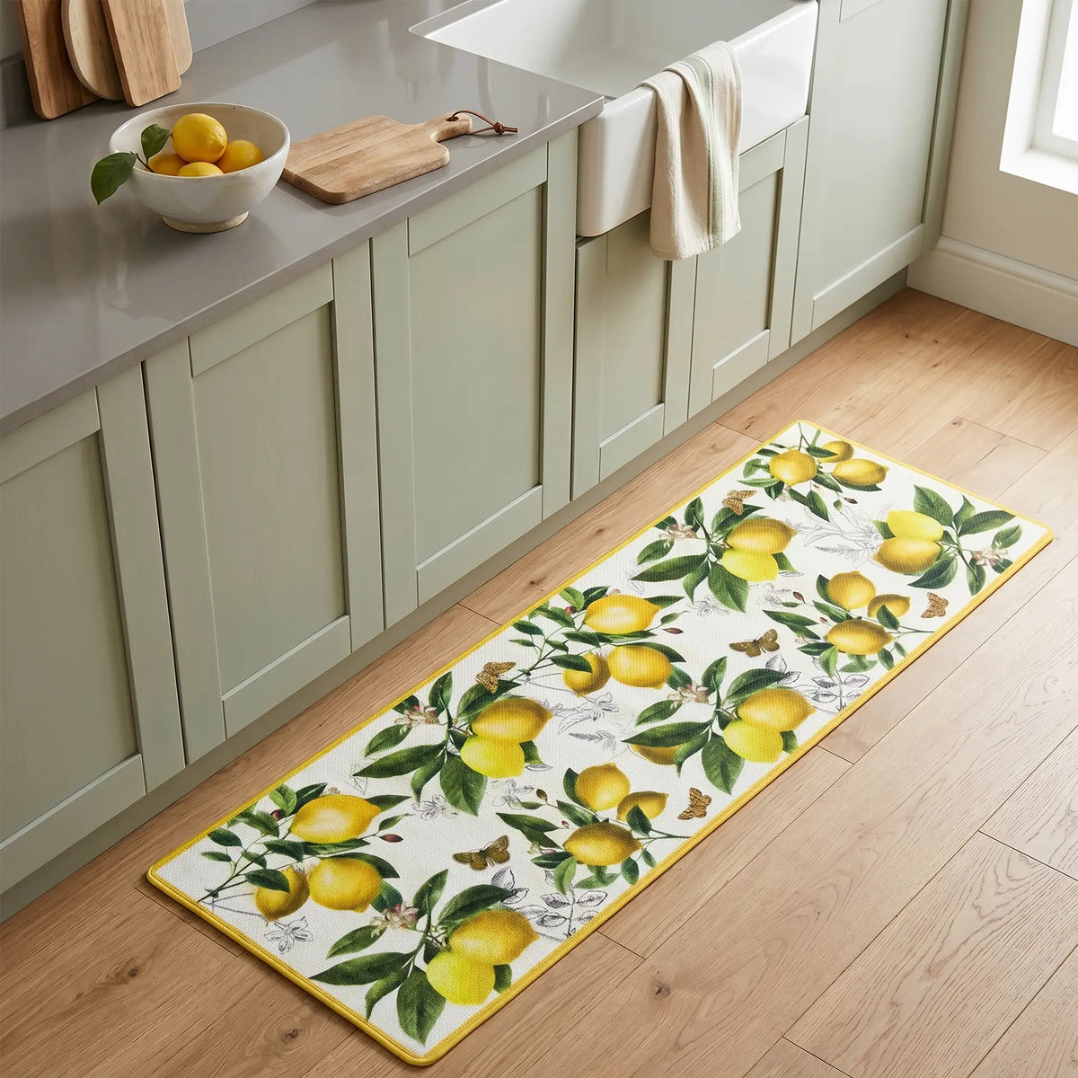 Tapete largo antifatiga de limones frescos (120x40 cm) colocado frente a gabinetes de cocina verdes, aportando comodidad y estilo natural - Tufan