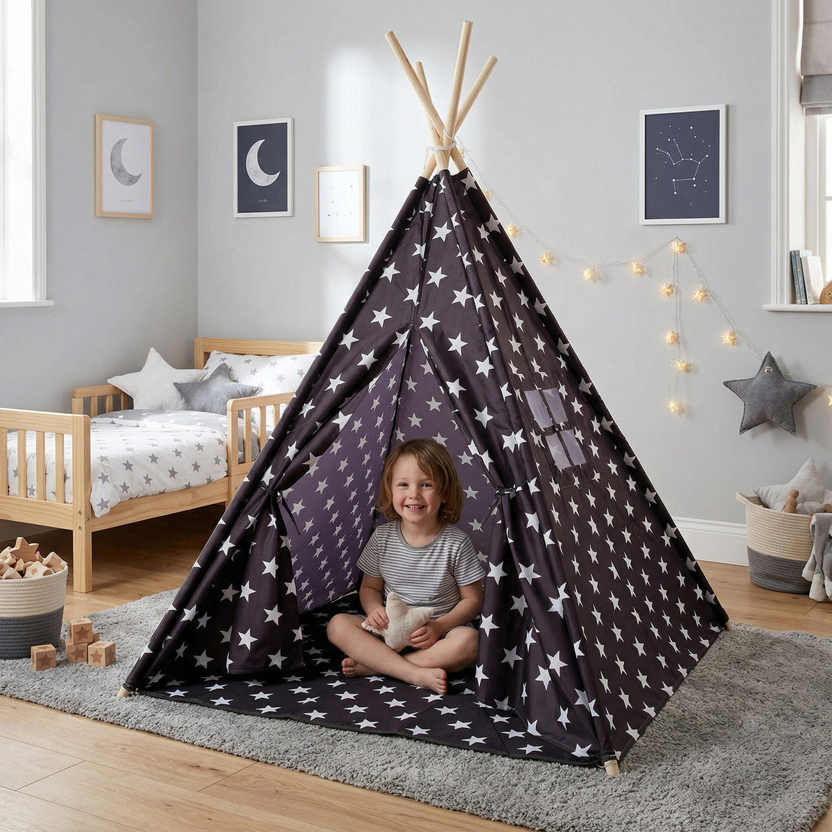 Niño sonriendo dentro de una tipi negra con estrellas blancas en una habitación con temática espacial, cama de madera y alfombra gris - Tufan