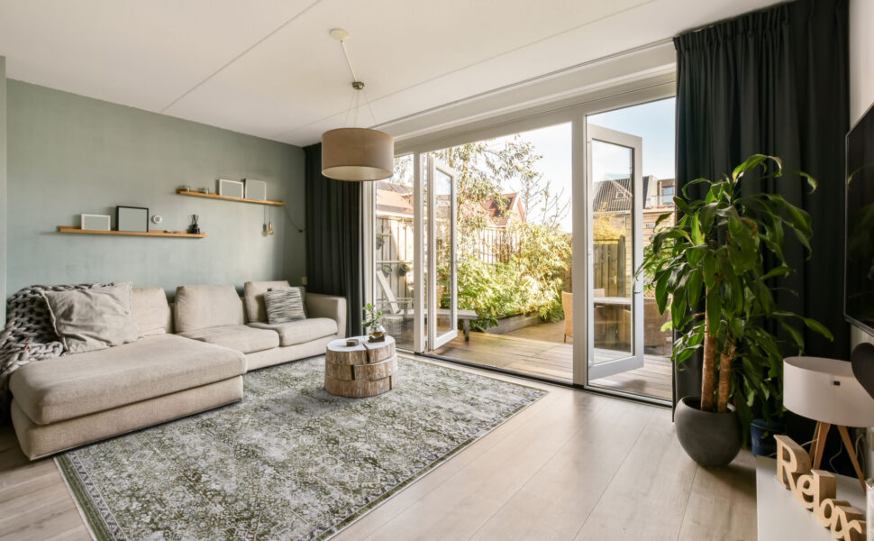 Living room with a corner sofa in front of a large TV and access to a cozy backyard in a modern house